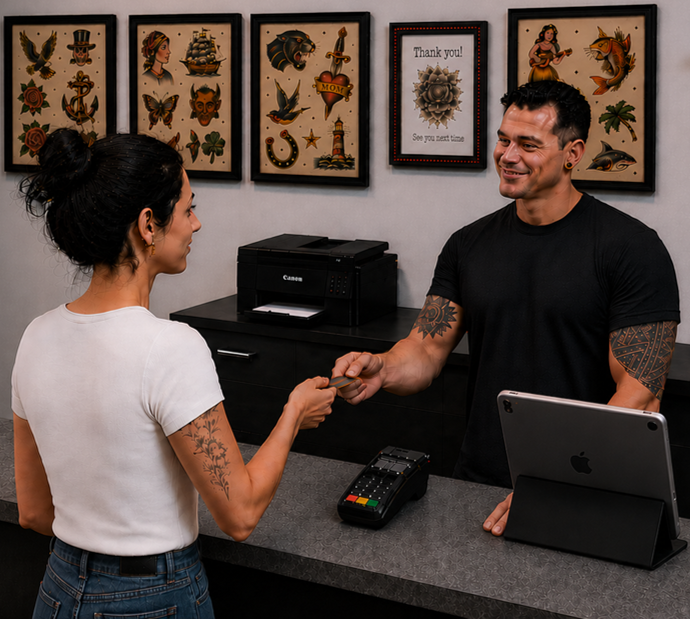 Tattoo artist assisting client at studio front desk as she pays after a professional, safety-focused tattoo session.